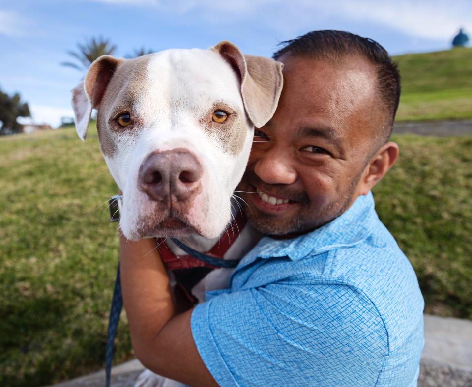 Smiling person hugging a dog outside